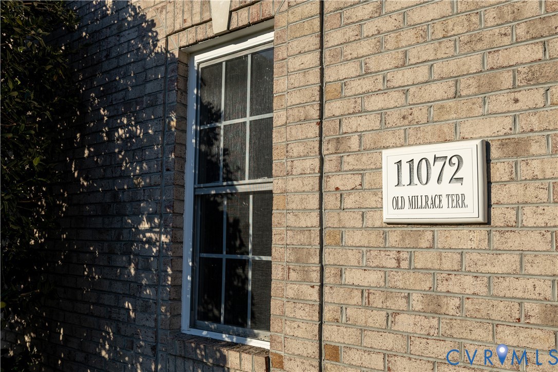 Exterior elevation featuring earth-toned brick masonry, double-hung window with a multi-pane upper sash, and custom address plaque