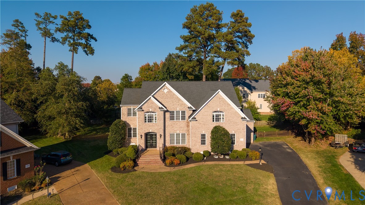 Multi-story brick exterior featuring a multi-gabled roofline, front-facing masonry steps, expansive lawn, mature trees, and a paved private driveway Multi-story brick exterior featuring a multi-gabled roofline, front-facing masonry steps, expansive lawn, mature trees, and a paved private driveway