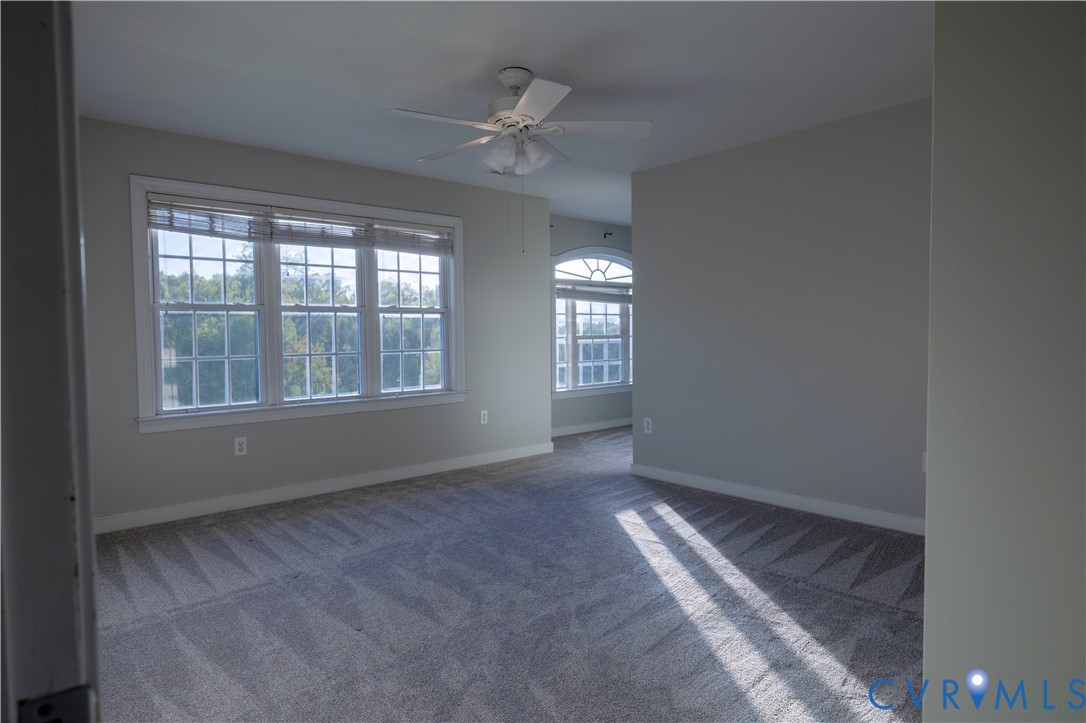 Multi-pane windows, arched accent window, ceiling fan with integrated lighting, and neutral wall-to-wall carpeting