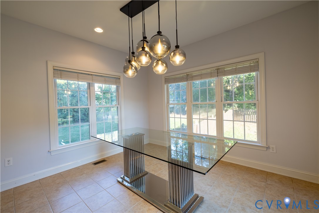 Multi-pane windows, neutral tile flooring, and a contemporary multi-globe chandelier featuring a black metal finish