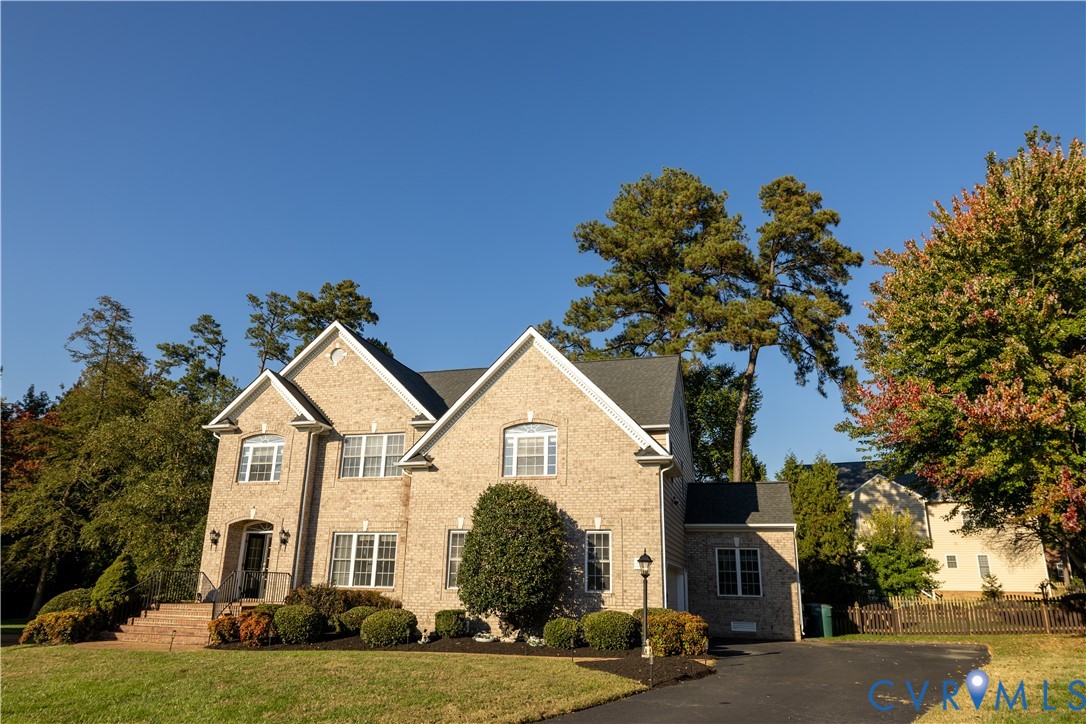 Multi-level brick exterior featuring a multi-gabled roofline, asphalt shingle roofing, multi-pane windows, and a paved driveway