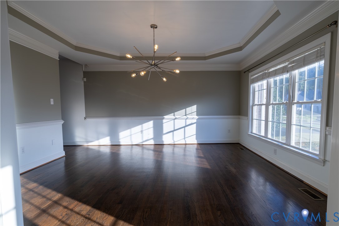 Tray ceiling featuring crown molding, multi-pane windows, wood-finish flooring, wainscoting, and a multi-arm sputnik-style chandelier