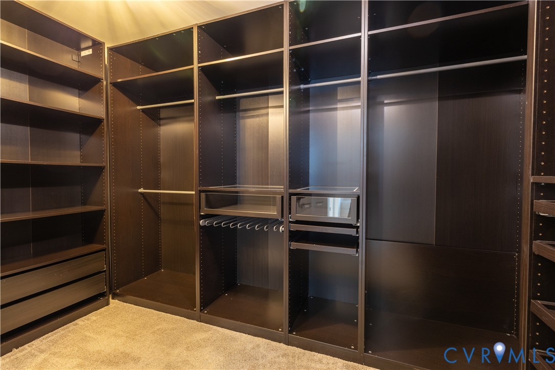 Custom dark-finish built-in closet organization system featuring adjustable shelving, integrated hanging rods, and glass-front storage drawers