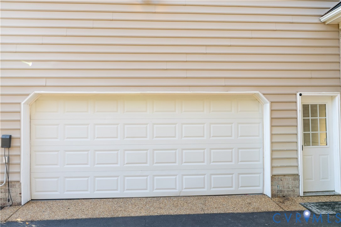 Horizontal lap siding exterior with a white paneled garage door and an attached service door featuring a multi-pane glass window