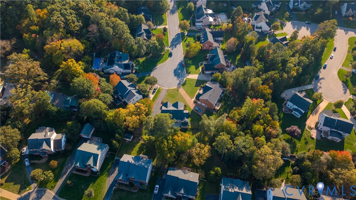 Aerial perspective of a suburban neighborhood featuring winding roads, cul-de-sacs, detached homes, and mature deciduous trees