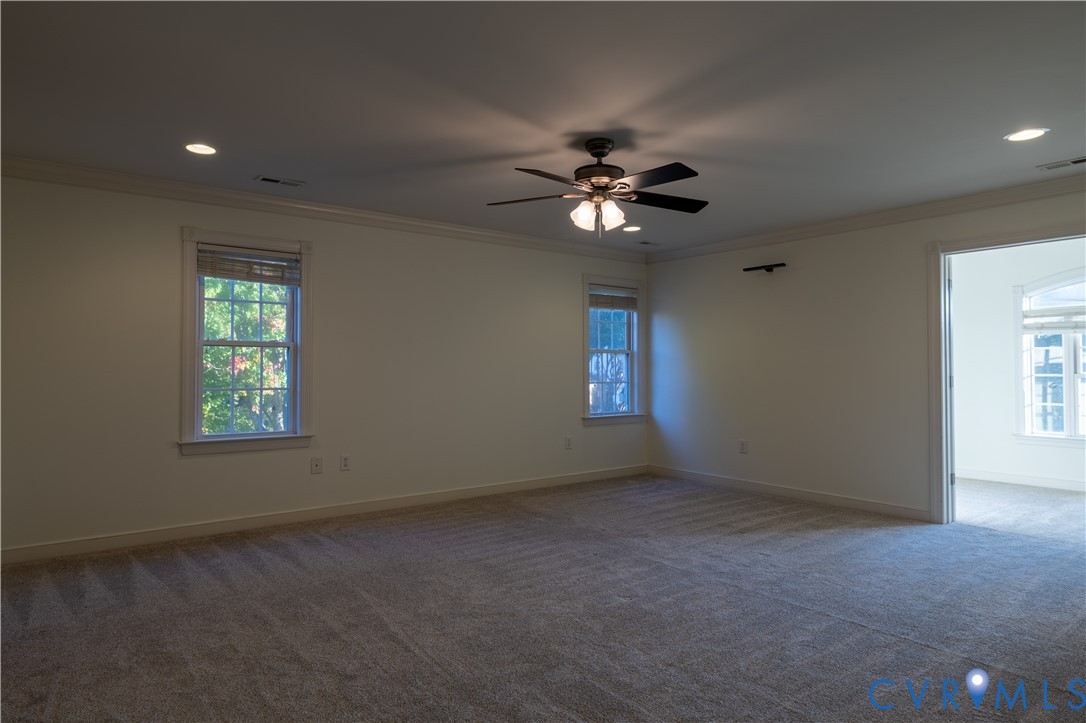 Spacious room featuring wall-to-wall carpeting, recessed lighting, crown molding, and a multi-blade ceiling fan with a central light fixture
