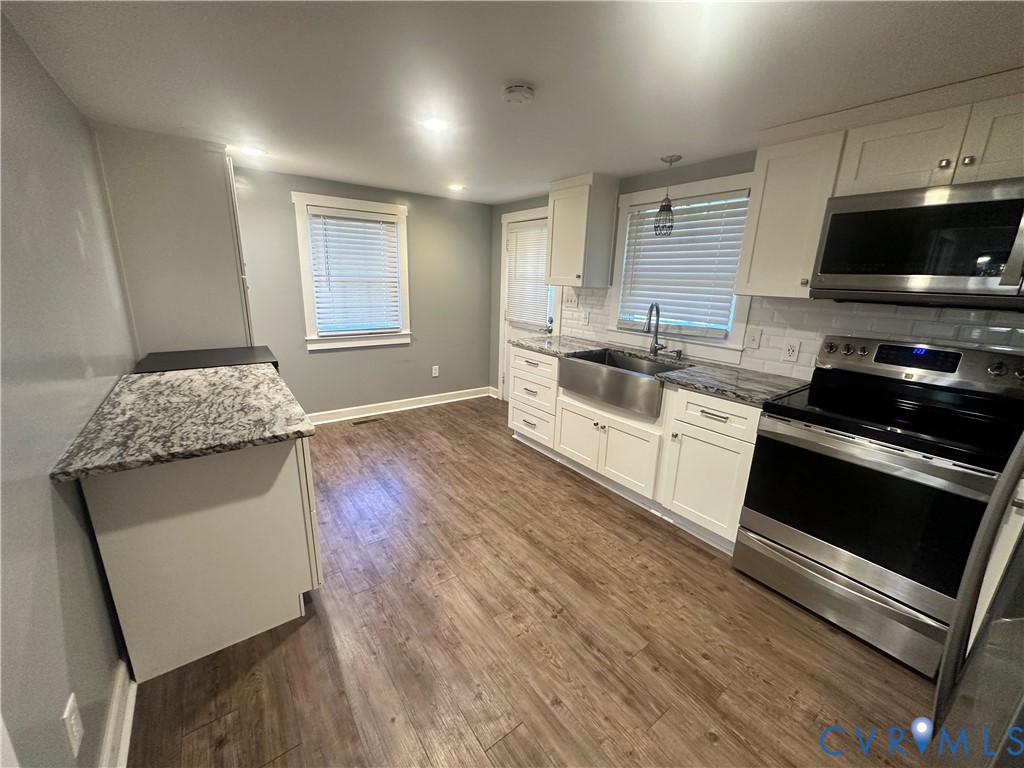 Updated kitchen with tile backsplash, LVP flooring,granite, stainless appliances and an island for seating.