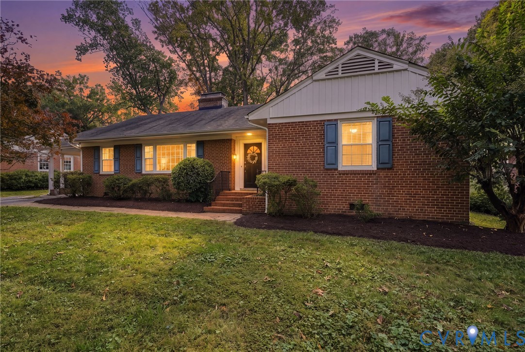 Traditional brick exterior featuring white vertical siding, dark shutters, a front chimney, and a multi-pane front door