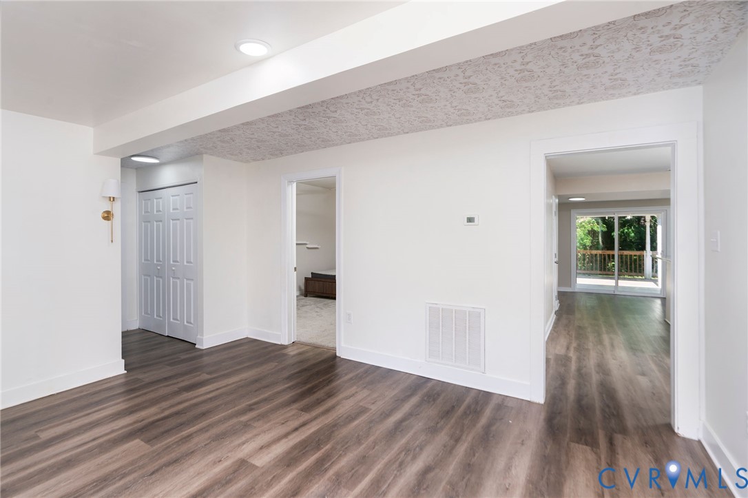 Interior space featuring wood-finish flooring, recessed lighting, wall-mounted light fixture, dual-panel closet doors, and patterned ceiling texture