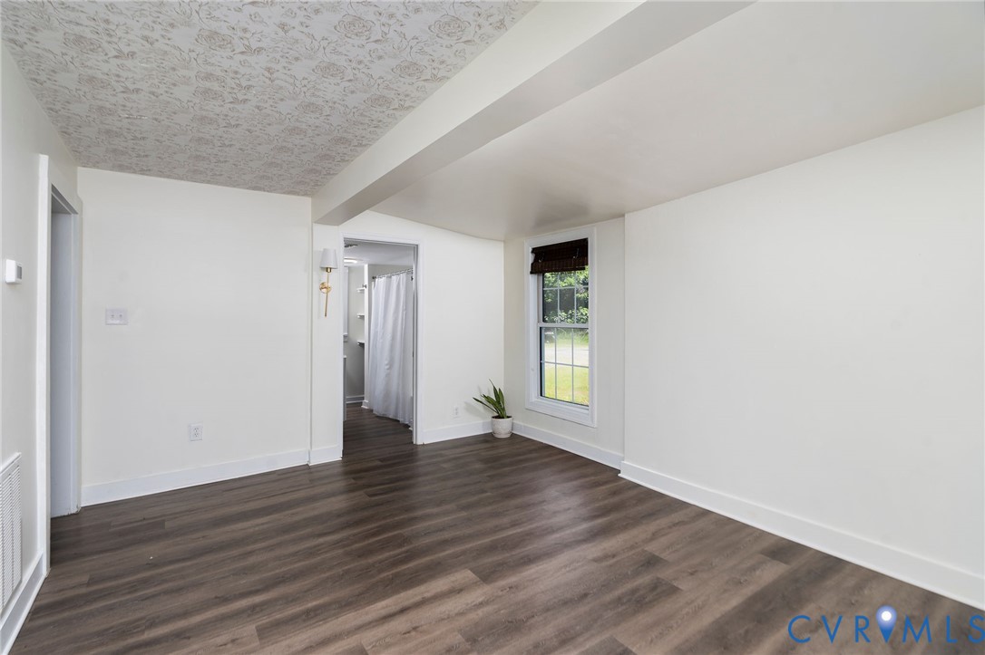 Interior space featuring wood-finish flooring, patterned ceiling detailing, a single-hung window with a roller shade, and wall-mounted brass lighting
