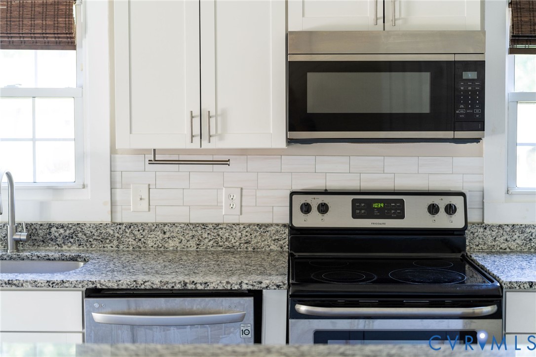 Kitchen featuring stone countertops, white cabinetry, subway tile backsplash, and stainless steel appliances