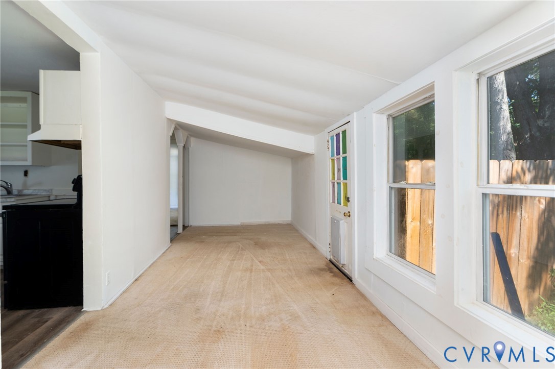 Sunroom featuring a vaulted ceiling, oversized windows, and a multi-pane glass door