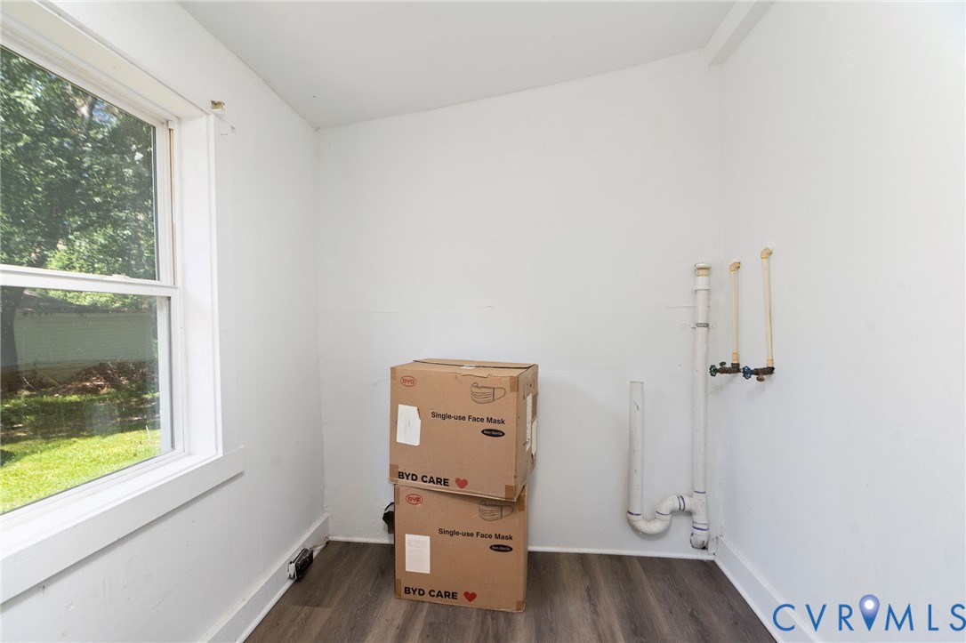 Utility space featuring wood-finish flooring, a large window, and plumbing hookups