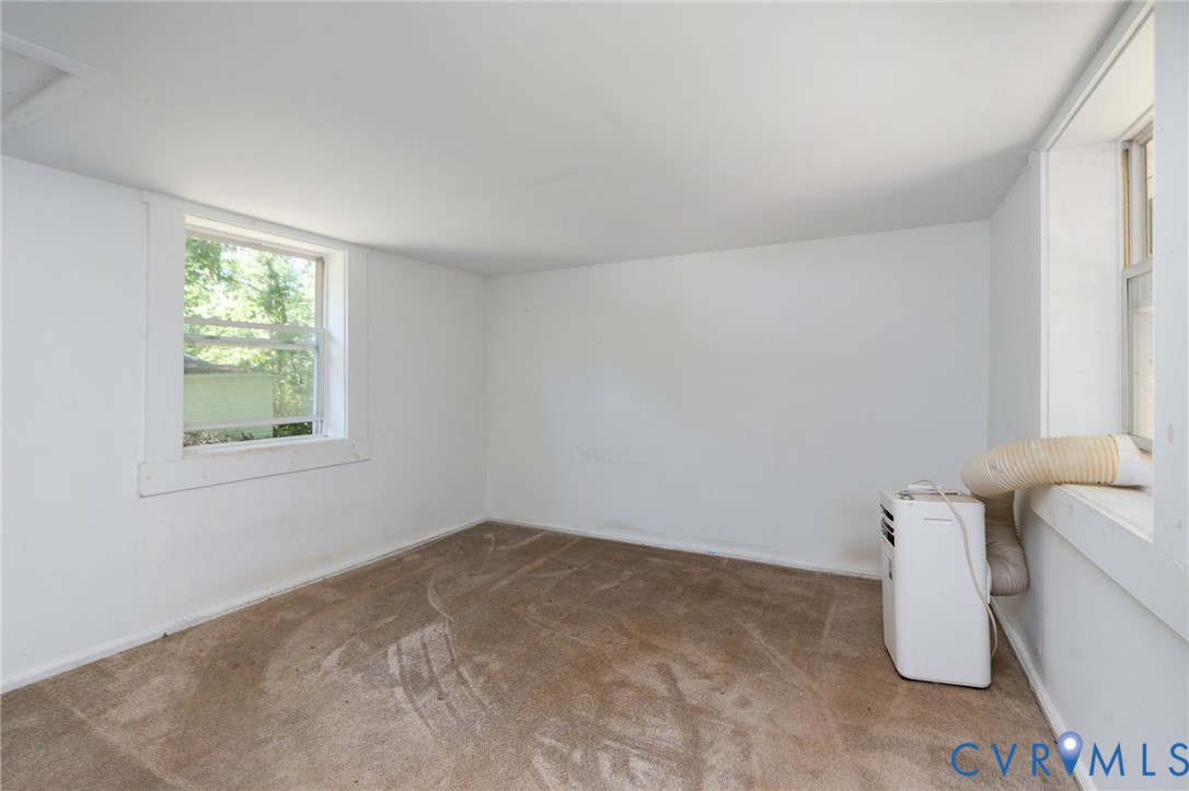 Neutral-toned wall-to-wall carpeting, white walls, and two double-hung windows