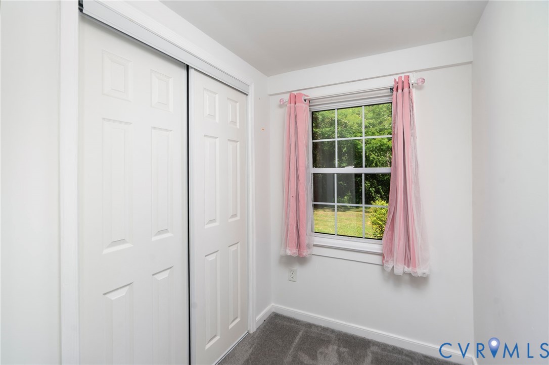 Room featuring sliding closet doors, wall-to-wall carpeting, and a multi-pane window
