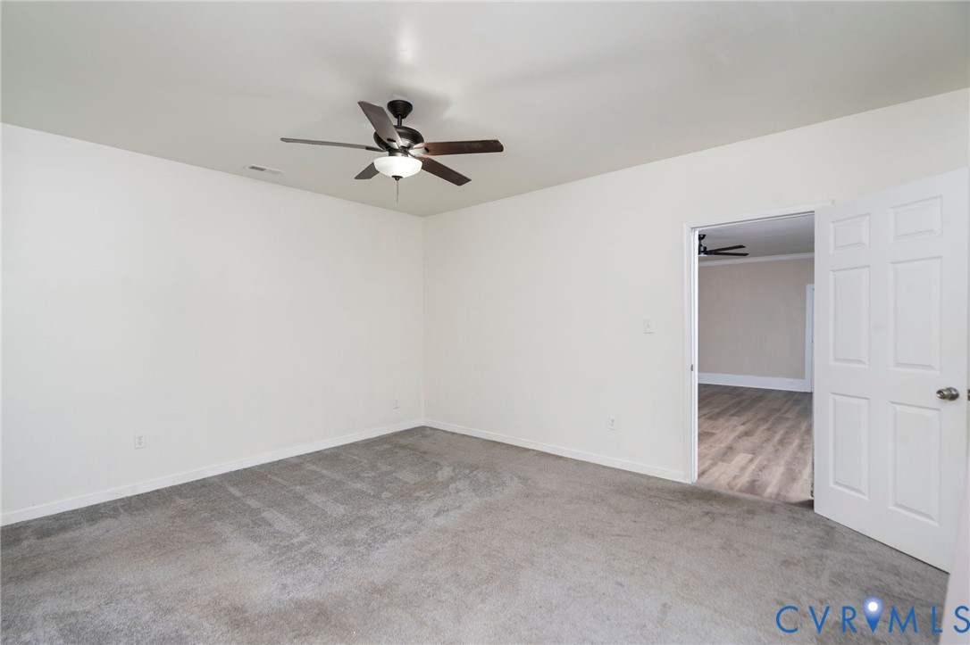 Interior space featuring neutral-toned carpeting, a ceiling fan with integrated lighting, and a multi-panel interior door