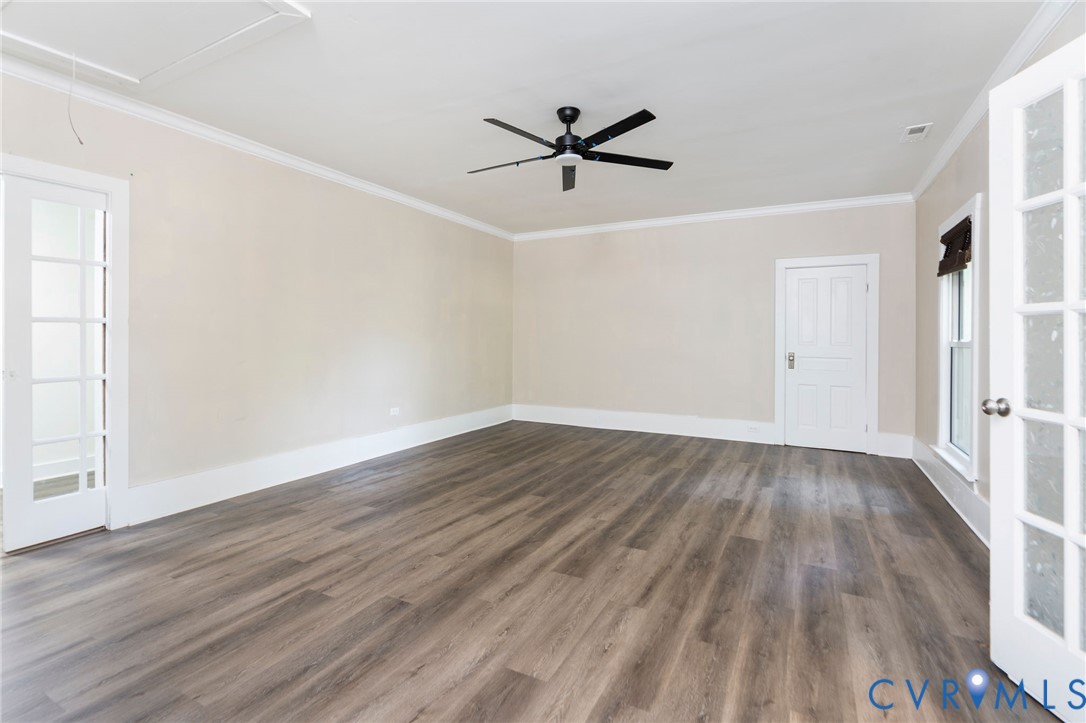 Interior room featuring wood-finish flooring, a ceiling fan with integrated lighting, crown molding, and two sets of French doors with glass panes
