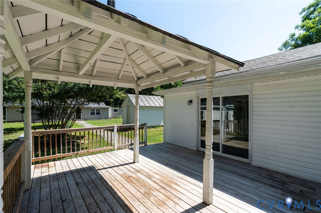Exterior wood decking featuring a covered gazebo structure with decorative pillars and sliding glass entry doors