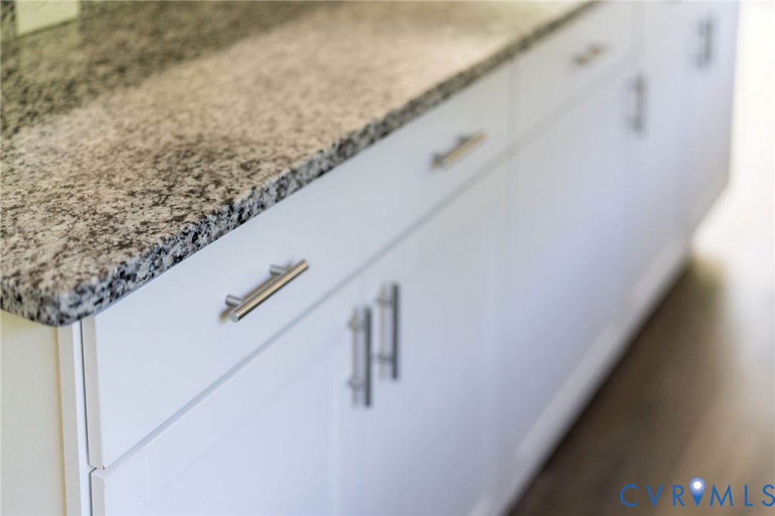 White shaker-style cabinetry with satin nickel bar pulls and a neutral-toned stone countertop