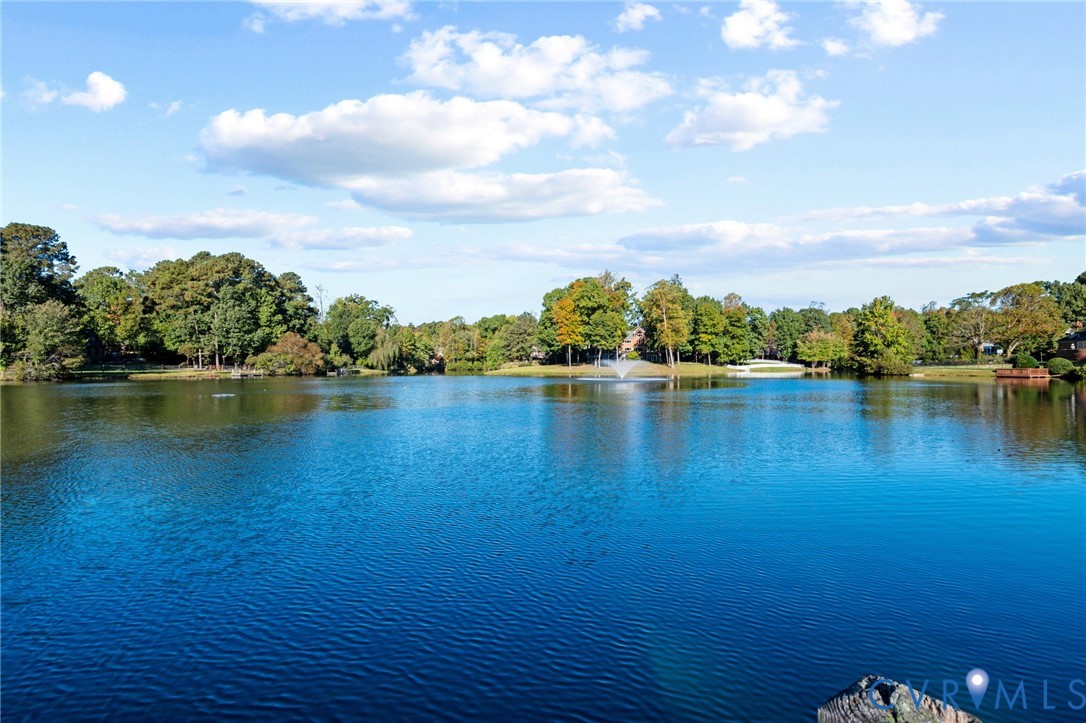 Waterfront setting featuring a centered fountain and mature perimeter trees