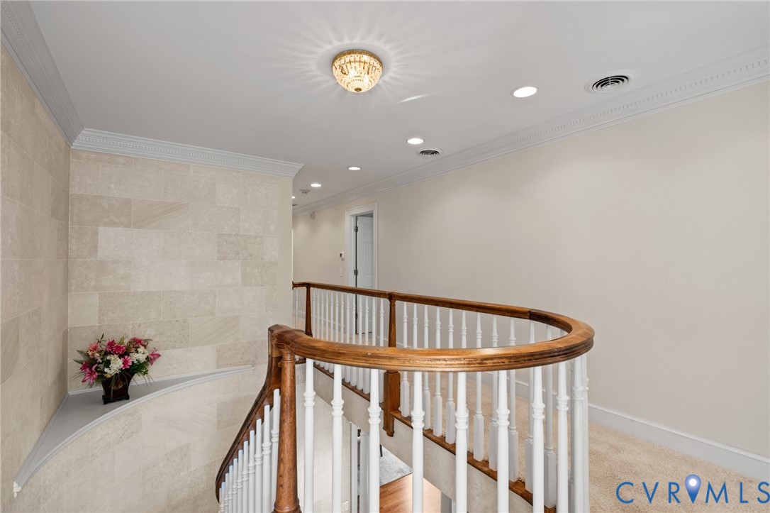 Curved staircase featuring a wooden handrail and white balusters, stone-tile accent wall, recessed lighting, and crown molding