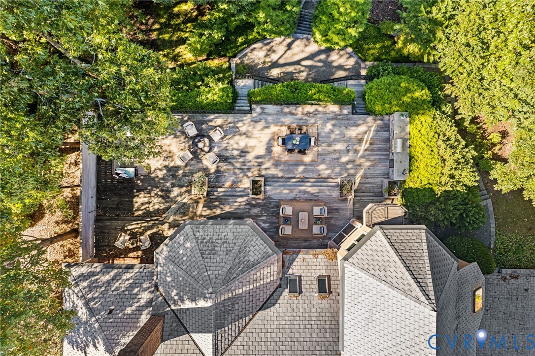 Multi-level wood deck featuring a built-in outdoor kitchen, stone hardscaping, tiered stairways, and mature landscaping