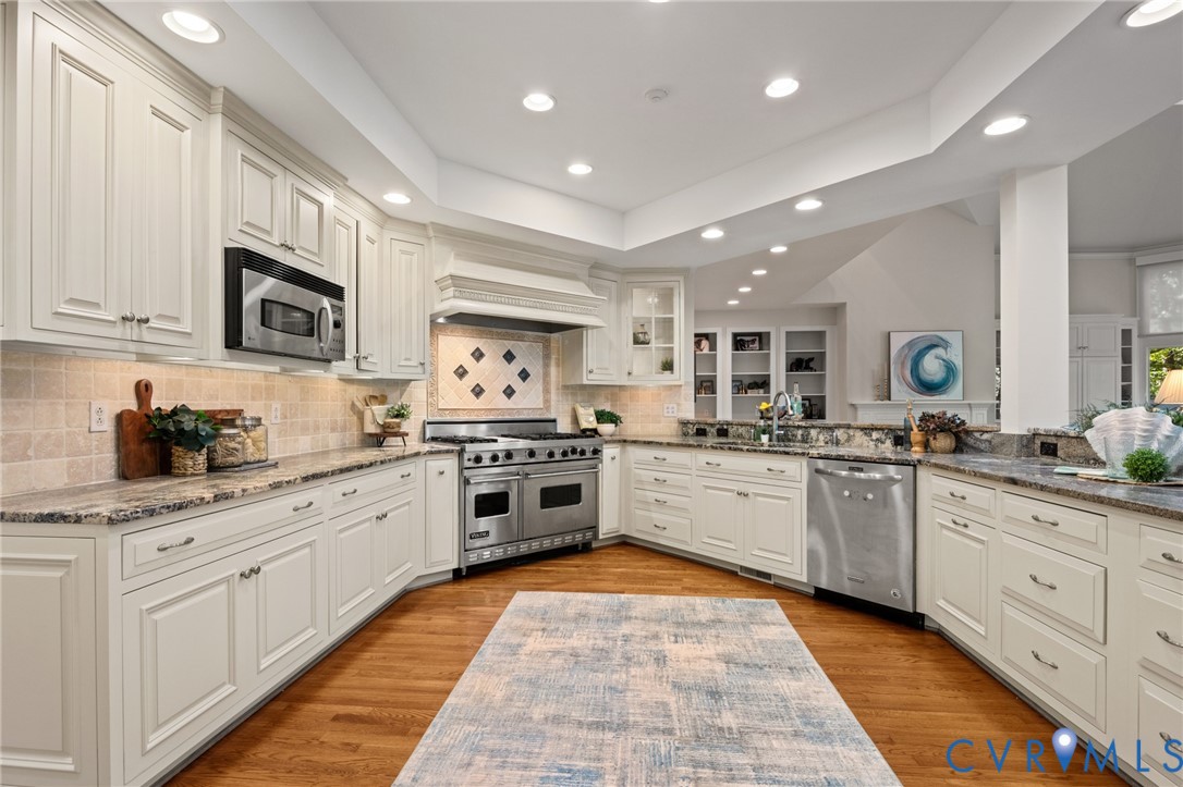 Kitchen featuring white cabinetry, stone countertops, wood-finish flooring, a stainless steel gas range, and recessed ceiling lighting