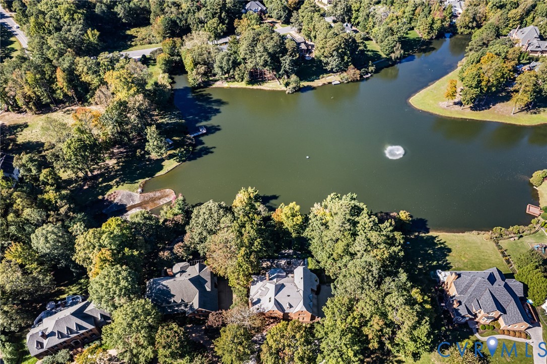 Aerial perspective of properties featuring waterfront access, expansive tree-lined surroundings, and established landscaping