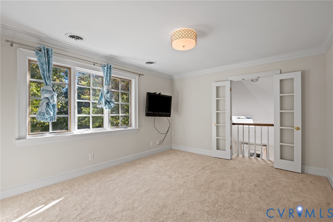 Room featuring wall-to-wall carpeting, crown molding, multi-pane windows, and a drum-style flush-mount ceiling light