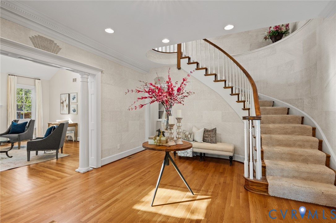 Foyer featuring curved staircase with wood handrail, white balusters, wood-finish flooring, recessed lighting, and crown molding