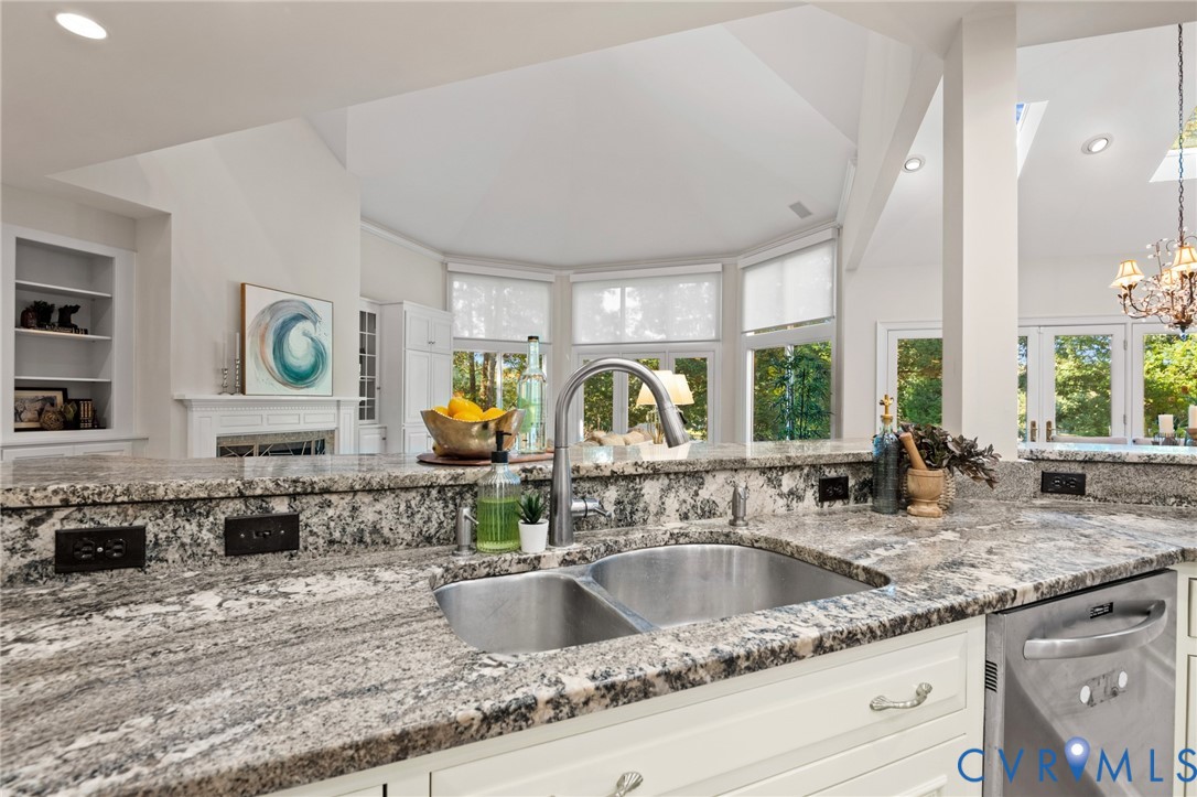 Kitchen featuring stone countertops, stainless steel dual-basin undermount sink, gooseneck faucet, white cabinetry, and recessed lighting