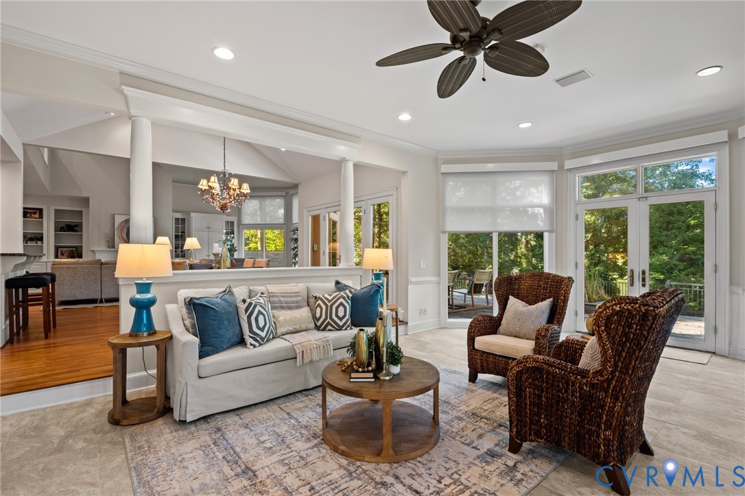 Open concept living area featuring tray ceilings, recessed lighting, architectural columns, tile flooring, and glass-paned double doors