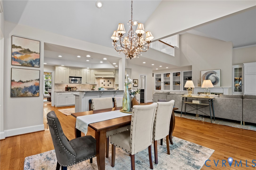 Vaulted ceiling, crystal chandelier, wood-finish flooring, built-in cabinetry, and recessed lighting