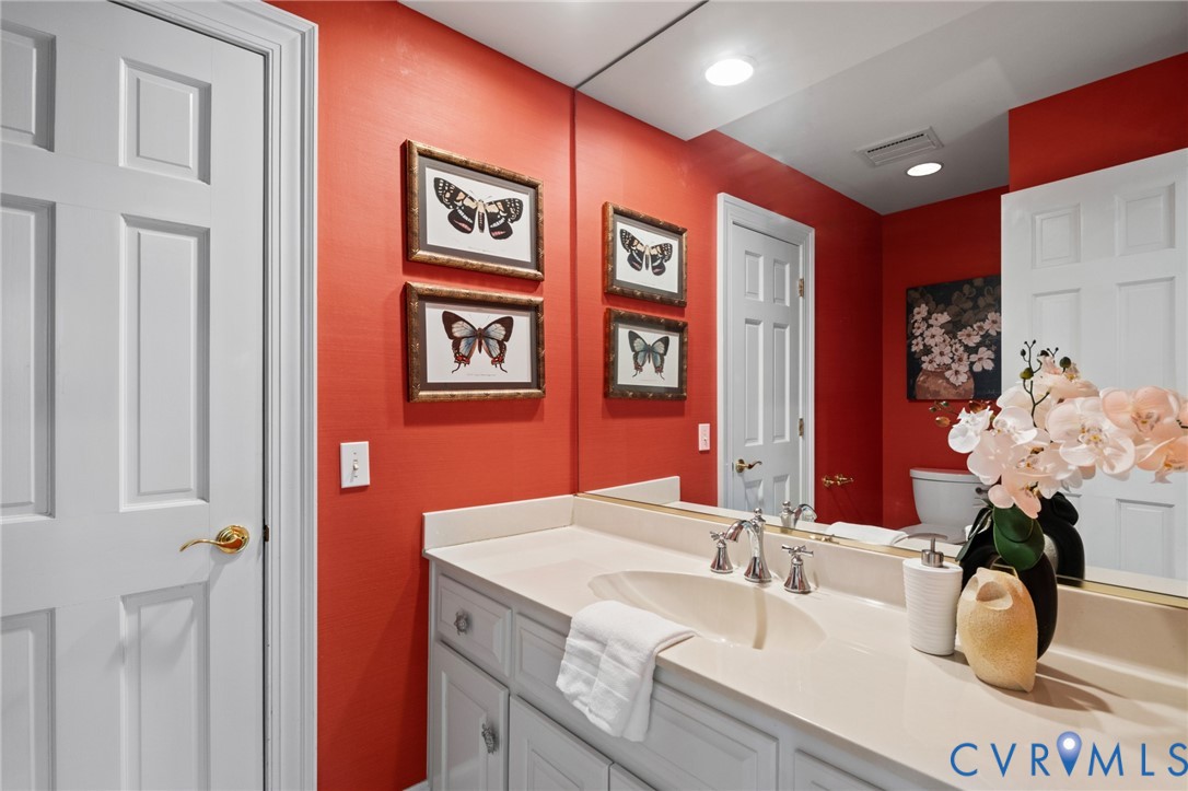 Bathroom vanity featuring a solid surface countertop, an integrated oval sink, and a multi-paneled cabinet base with hardware, paired with a full-width wall mirror and polished metal faucet fixtures
