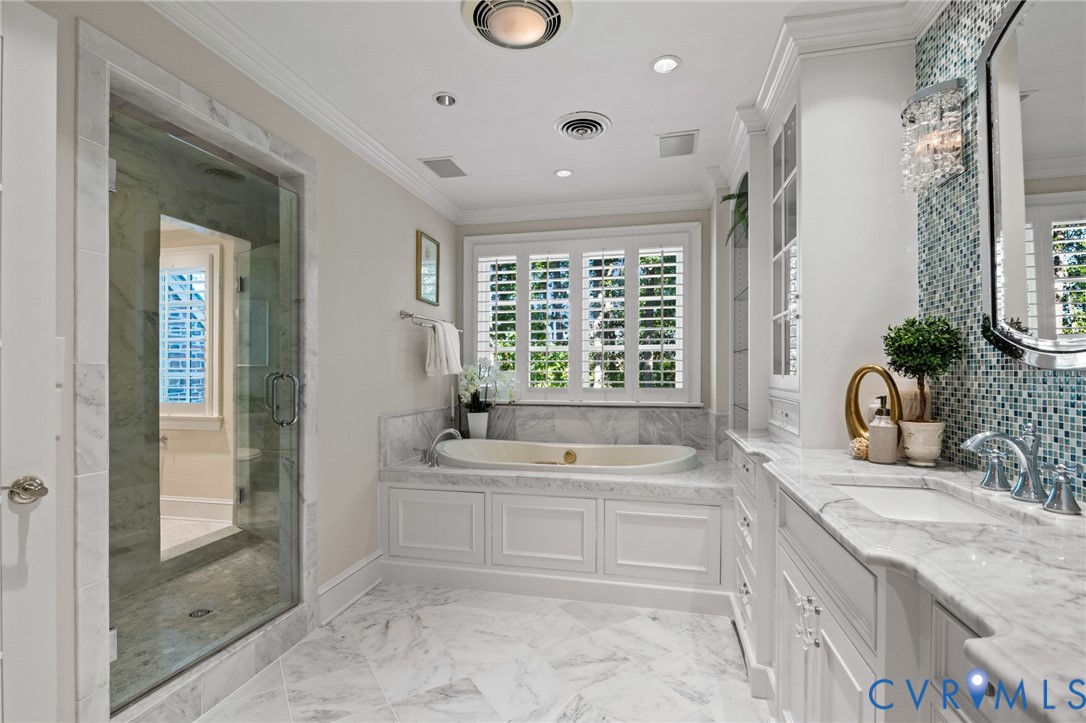 Bathroom featuring white cabinetry, stone-surface countertops, soaking tub, walk-in glass-enclosed shower, and decorative tile backsplash