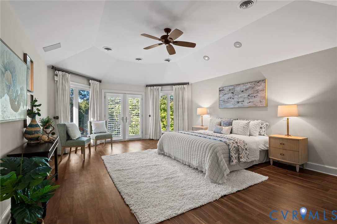 Vaulted ceiling with recessed lighting and a central ceiling fan, wood-finish flooring, and double glass-paneled exterior doors with plantation shutters