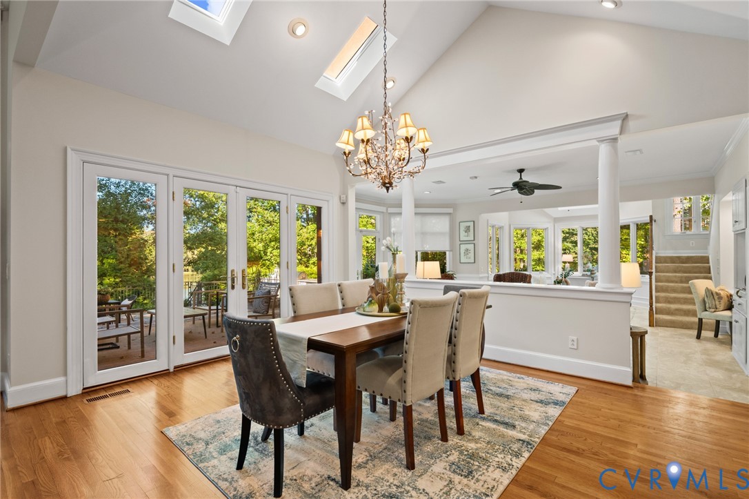 Vaulted ceiling featuring skylights, chandelier lighting, wood-finish flooring, and double glass-paned doors