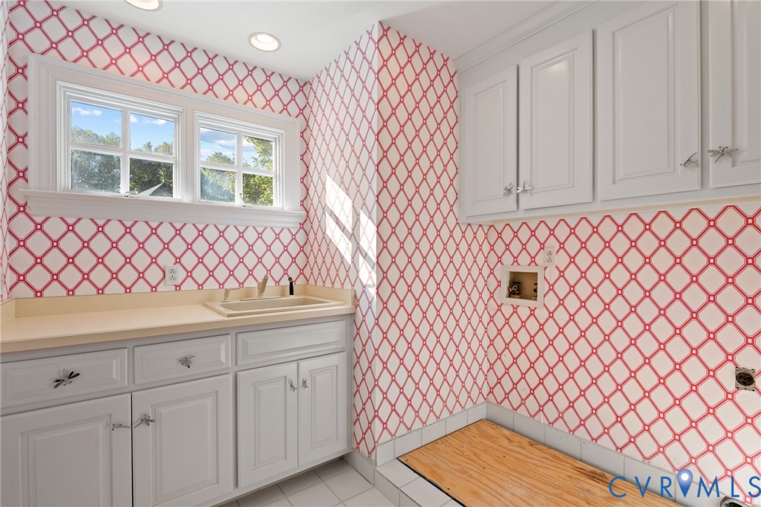 Utility room featuring white shaker-style cabinetry, a built-in drop-in sink with a solid surface countertop, recessed ceiling lighting, and a multi-pane window