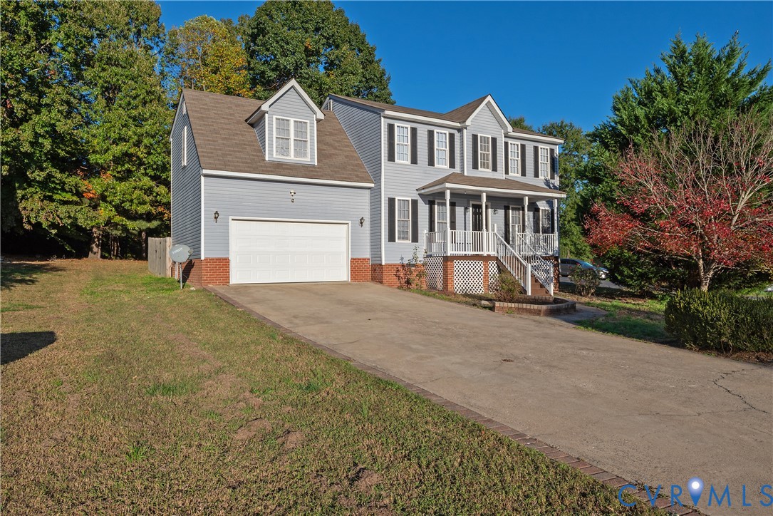 Two-story exterior featuring blue siding, a brick foundation, a front porch with white railing, and an attached two-car garage