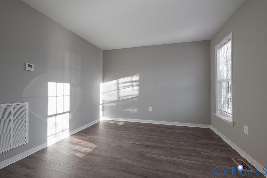 Living Room featuring neutral-toned wall paint, new flooring, and a single double-hung window with built-in blinds