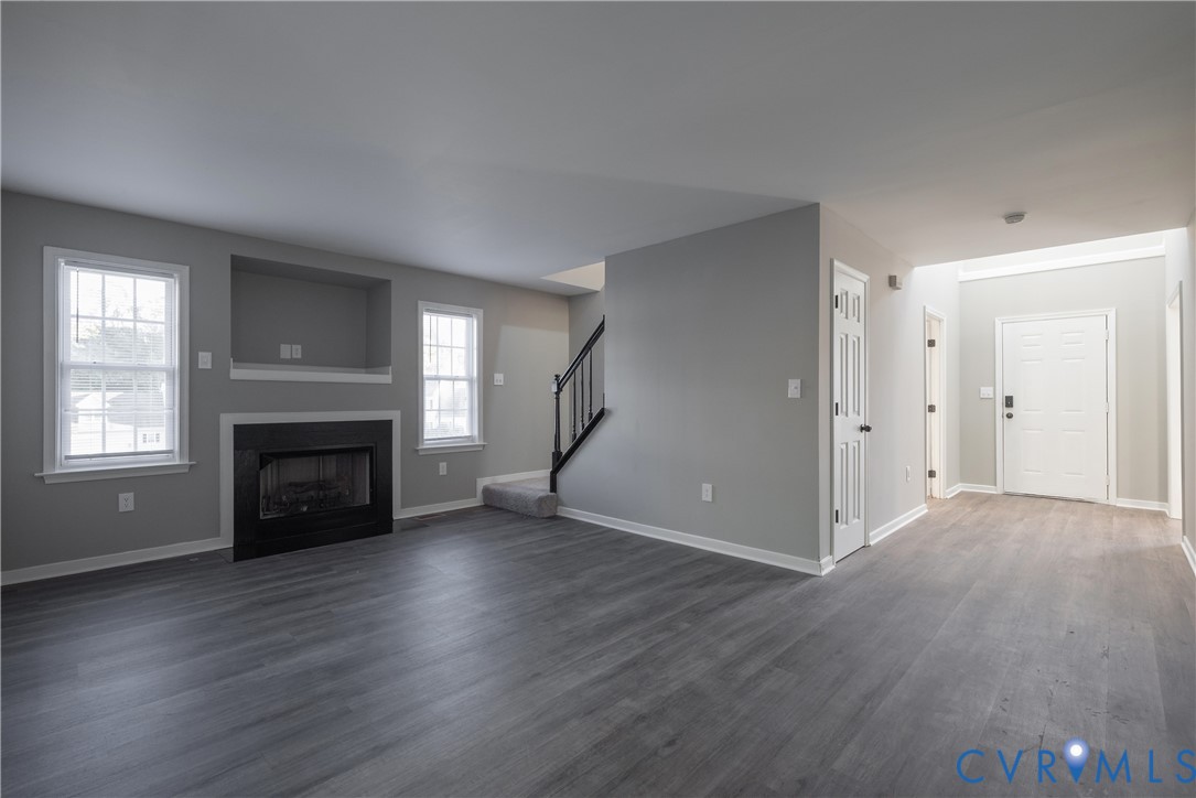 Family Room with a fireplace and recessed media niche, and a staircase featuring a black balustrade
