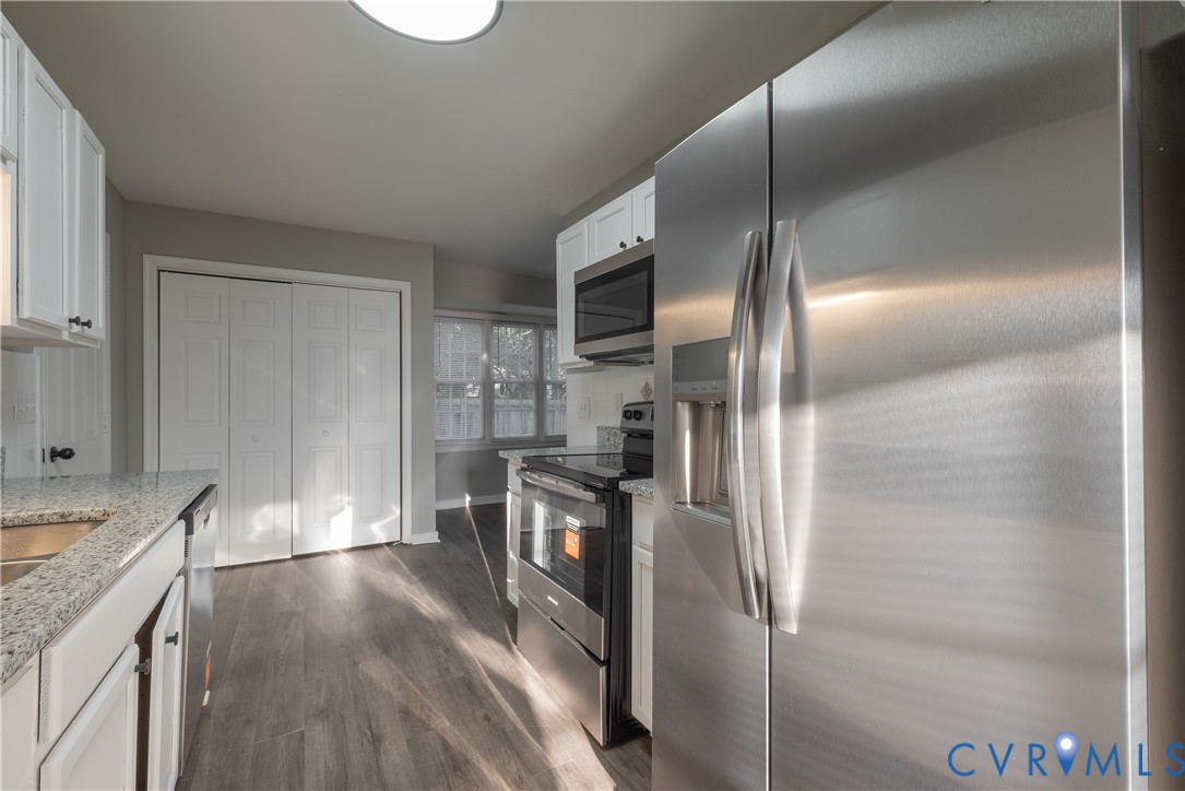 Kitchen featuring stainless steel appliances, granite countertops, white shaker-style cabinetry, and pantry