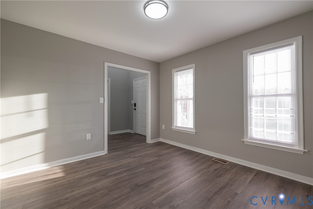 Formal Dining Room with new flooring, dual windows with blinds, and a flush-mount overhead light fixture
