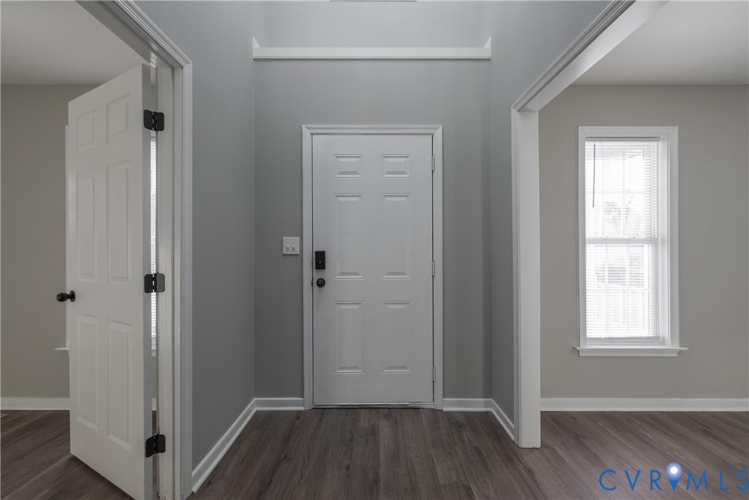 2 Story Entrance  featuring six-panel interior doors, wood-finish flooring, neutral wall paint, and a double-hung window