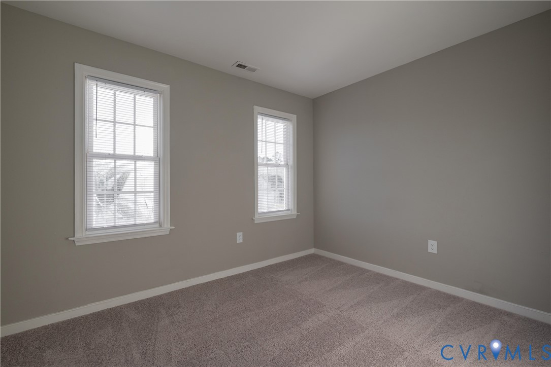 Bedroom #3 with neutral-toned room featuring wall-to-wall carpeting and dual double-hung windows with colonial-style grilles