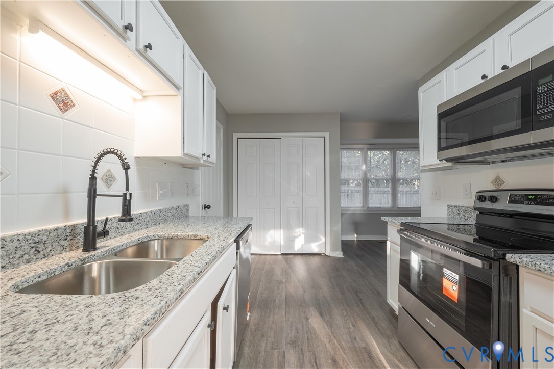 Kitchen featuring white cabinetry, granite countertops, and tile backsplash