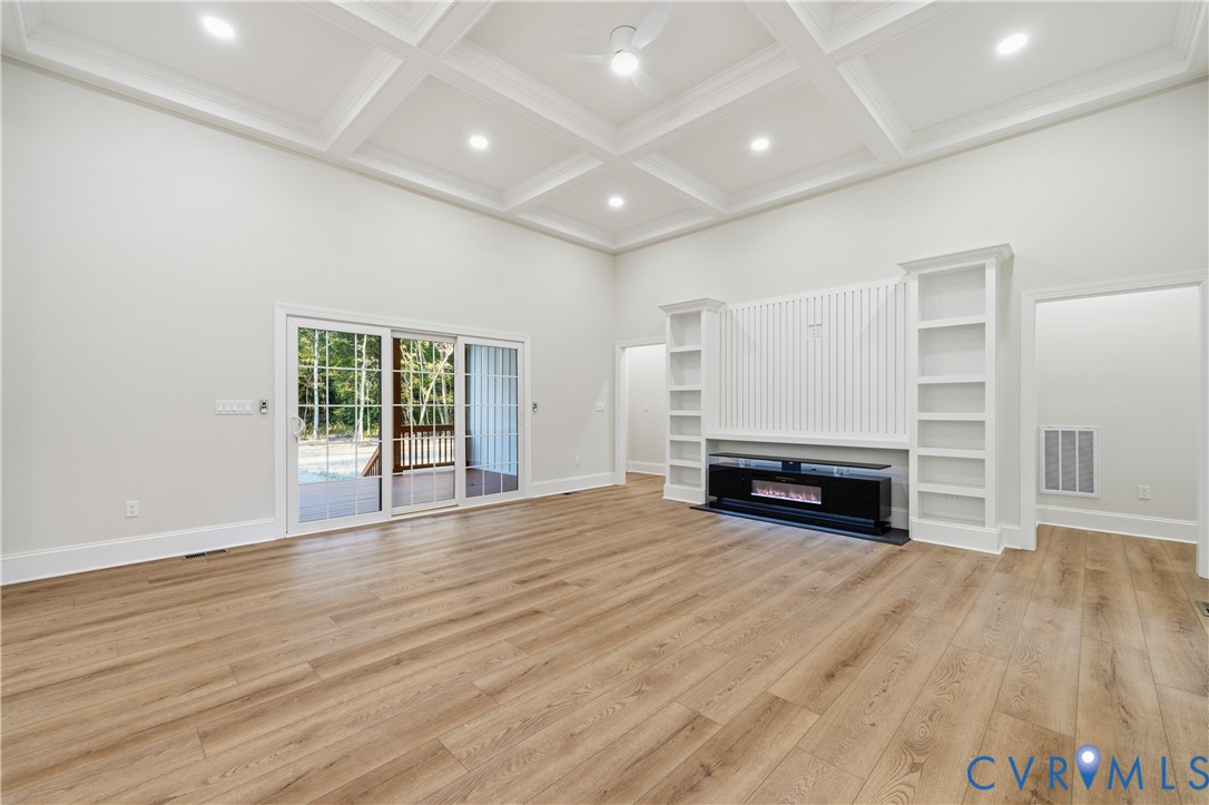 Coffered ceiling, wood-finish flooring, built-in cabinetry, recessed lighting, and sliding glass doors