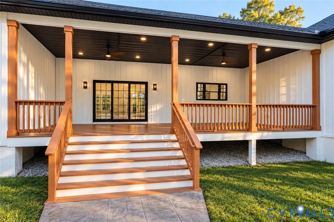 Covered porch featuring vertical siding, wooden support pillars, recessed ceiling lighting, dual ceiling fans, and wooden railings