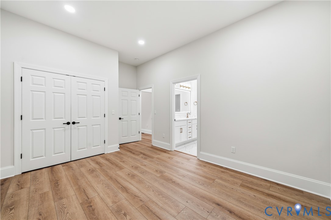 Interior space featuring wood-finish flooring, recessed lighting, and white six-panel doors with matte black hardware