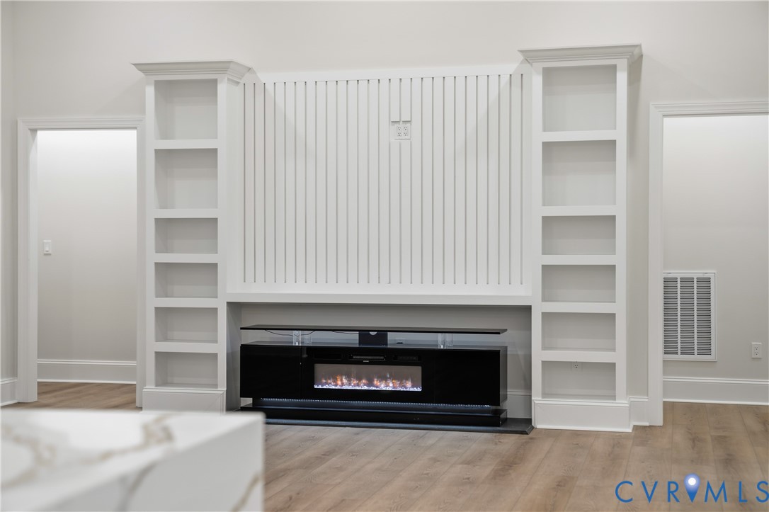 Built-in floor-to-ceiling shelving, vertical slat wall detailing, and an integrated fireplace unit featuring wood-finish flooring